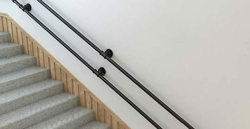 Détail d'une main courante murale en inox avec signalétique PMR dans un couloir lumineux d'établissement